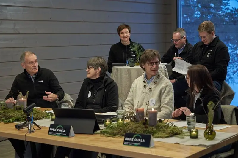 A group of five individuals seated at a table, each using laptops, engaged in a collaborative work session.