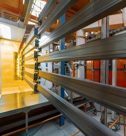 A spacious room filled with metal bars, illuminated by a warm yellow light, creating a stark and industrial atmosphere.