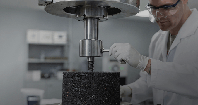 A man wearing a lab coat is engaged in examining a black object, demonstrating a scientific process in a lab environment.