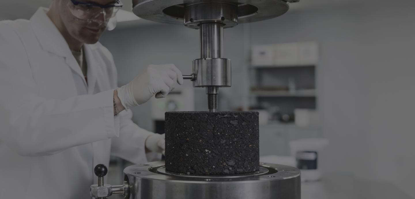 A man wearing a lab coat is engaged in examining a black object, demonstrating a scientific process in a lab environment.